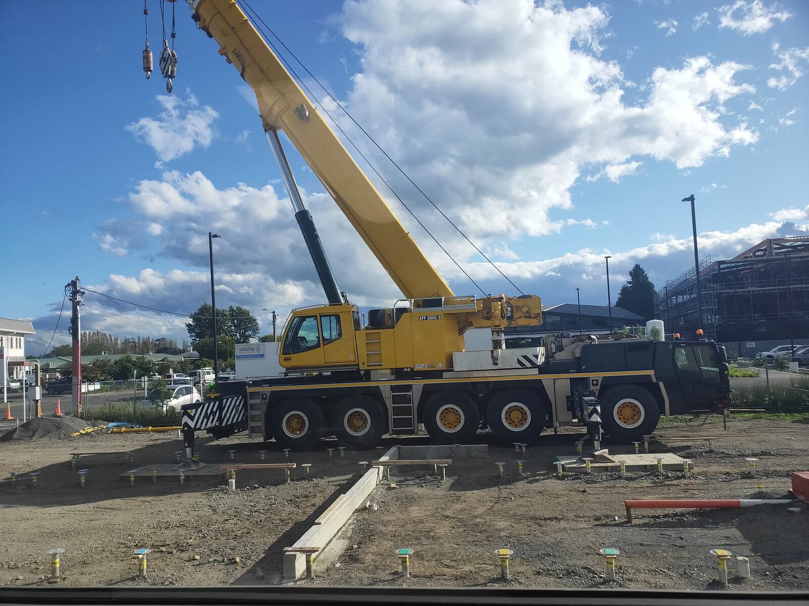 A mobile crane set up over the finished foundation pads, ready to lift the modules into place