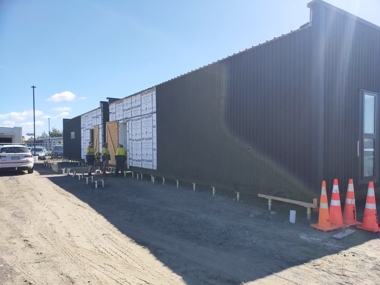 The clinic modules landed in a row on their foundation piles, building wrap still in place
