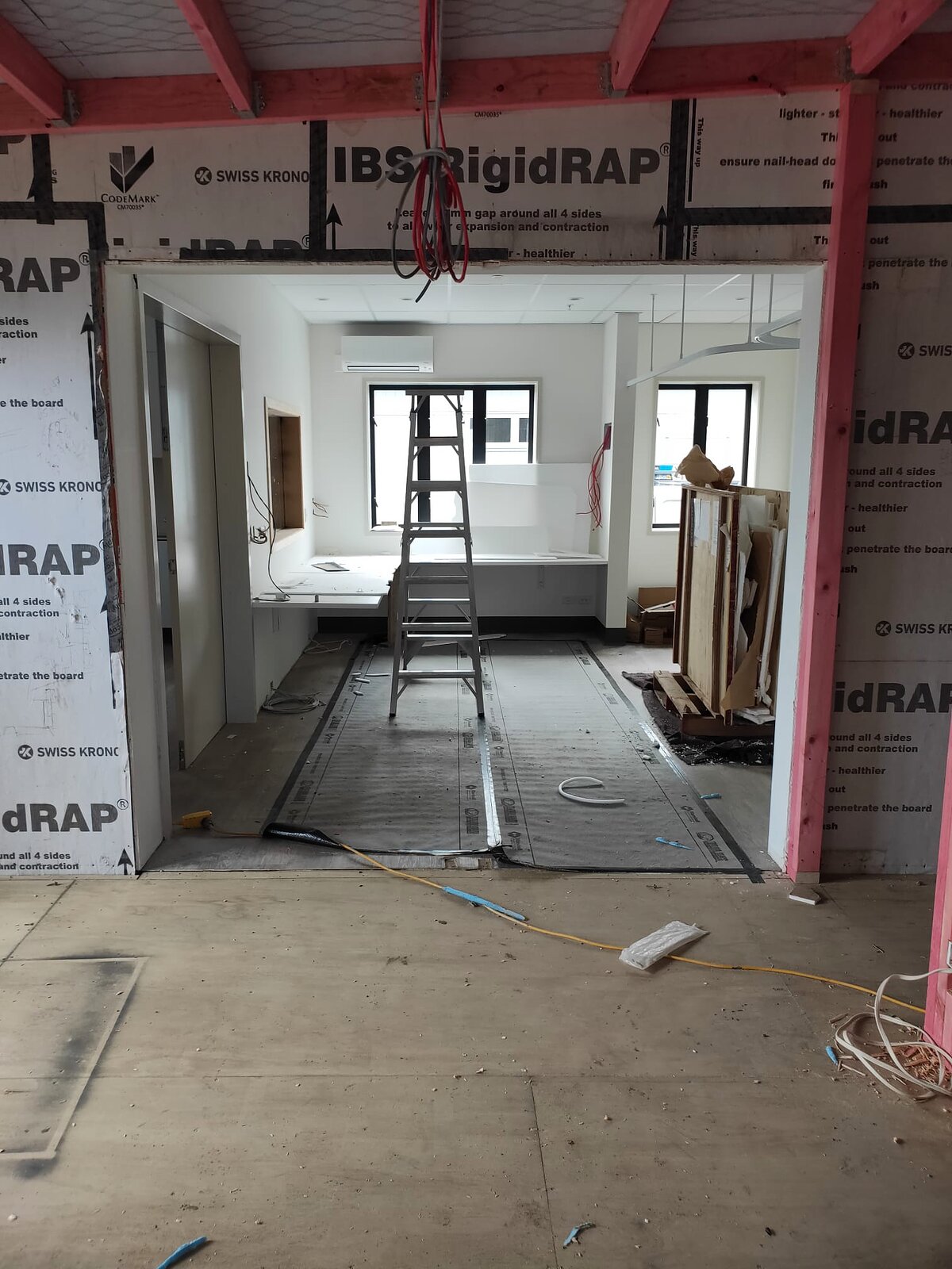 Interior partitions under way, looking through wrapped framing into a completed white-lined room
