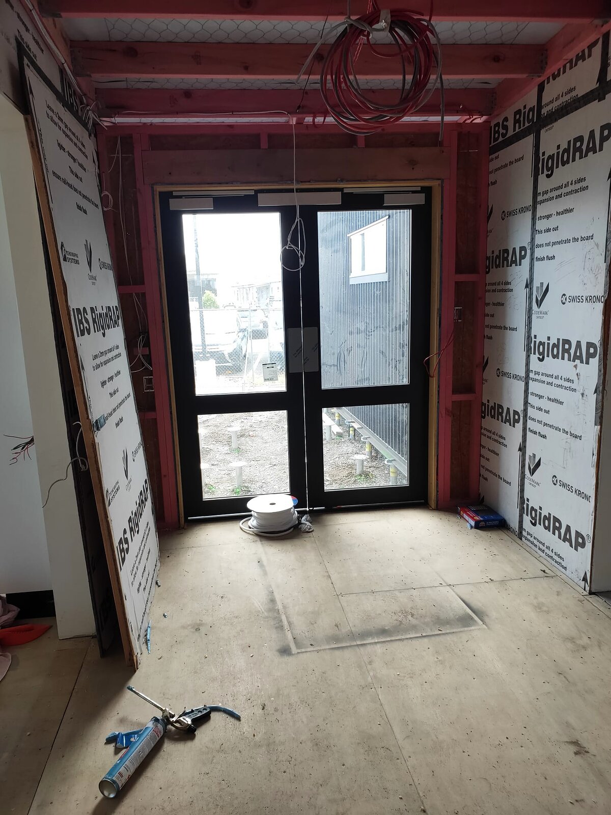 The glazed entry doors installed, seen from inside with wall wrap still on the surrounding framing