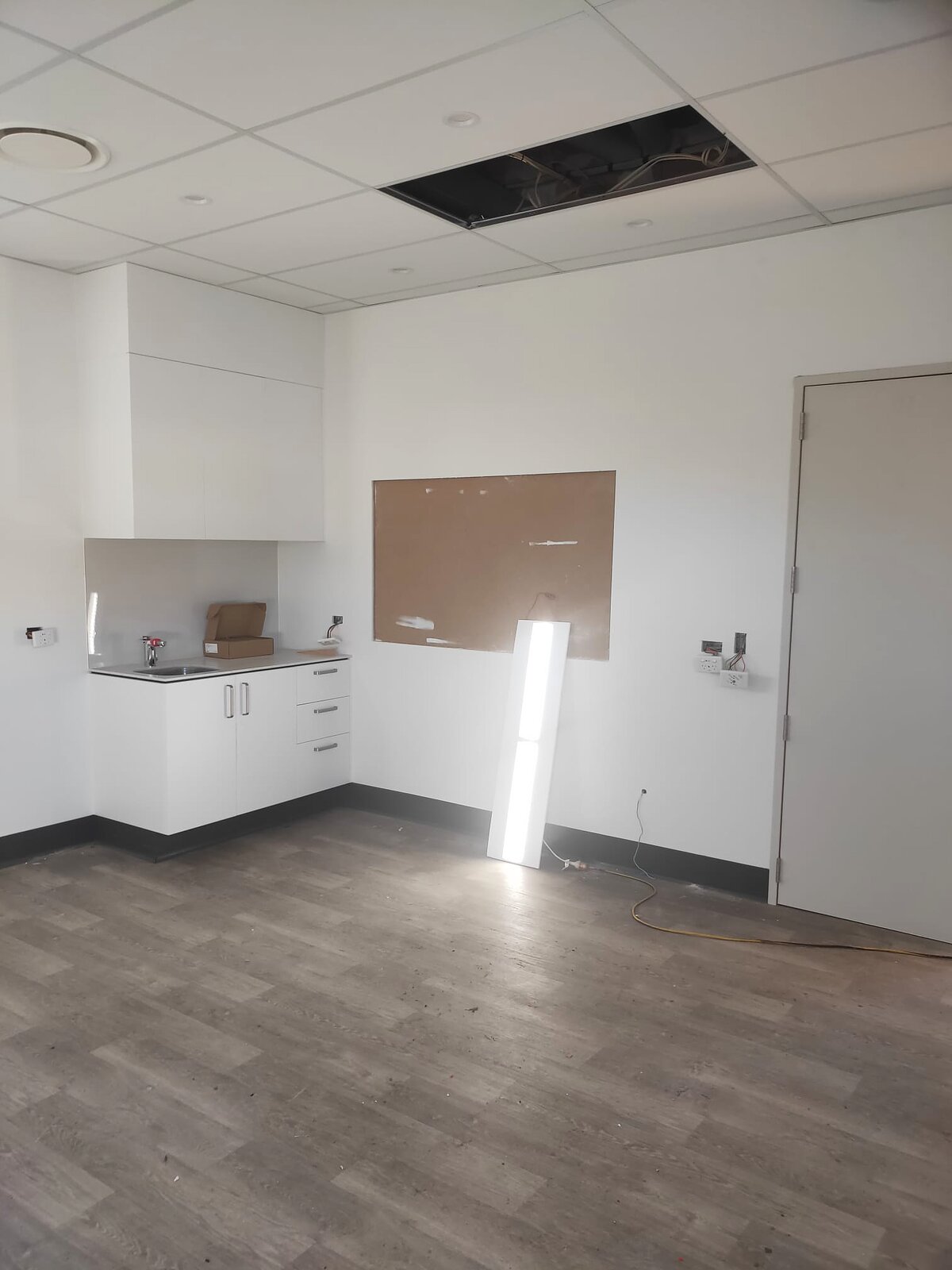 A completed clinic room with vinyl flooring, a corner bench with sink and a wall-mounted pinboard
