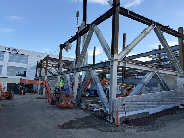 A structural steel truss being lifted into place on the ground floor frame